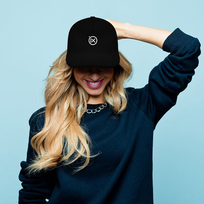 Black baseball cap with Ix logo worn by person with long blonde hair