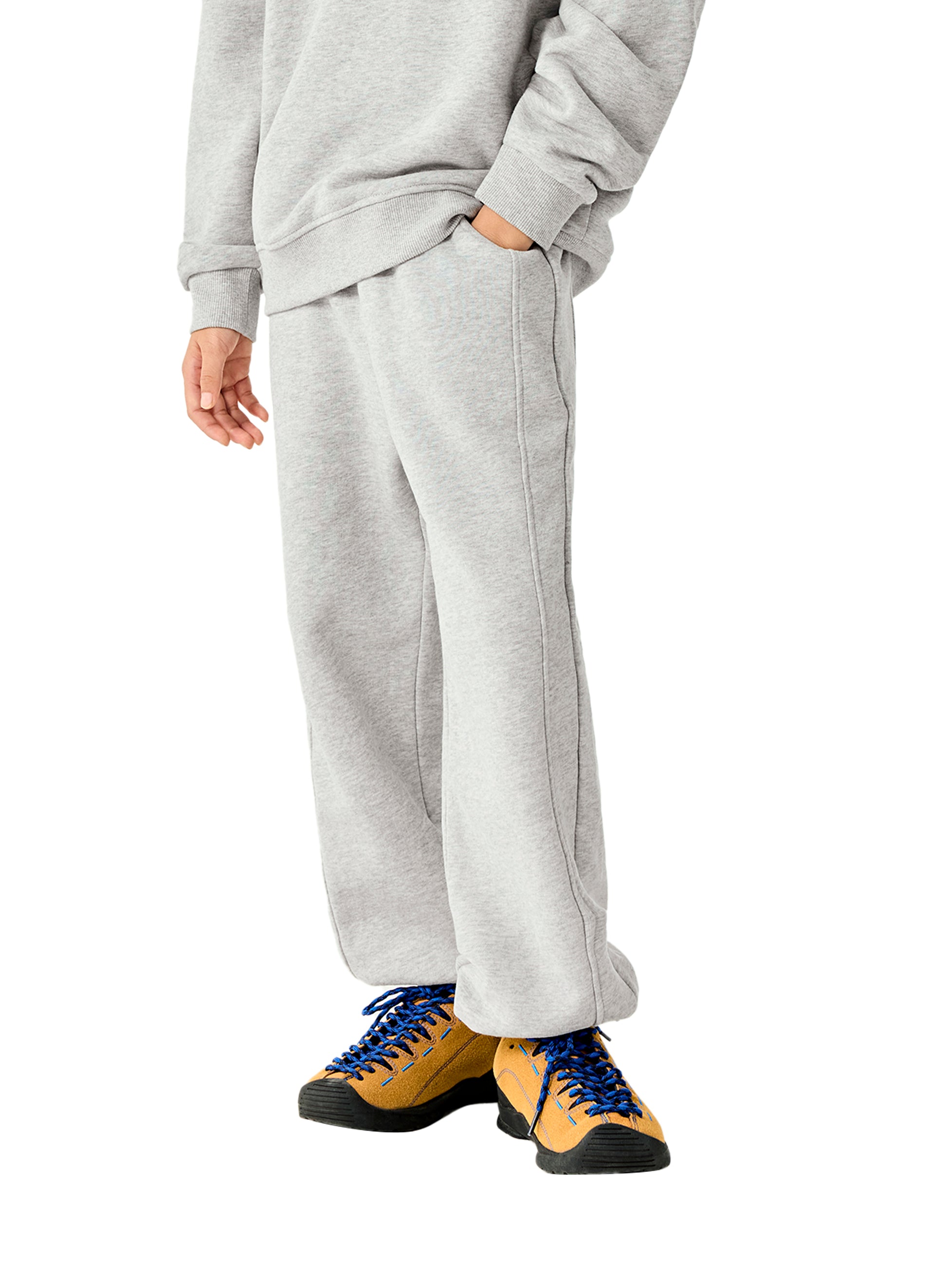 Kids fleece jogger in light gray worn with sneakers, elastic waistband and cuffed legs