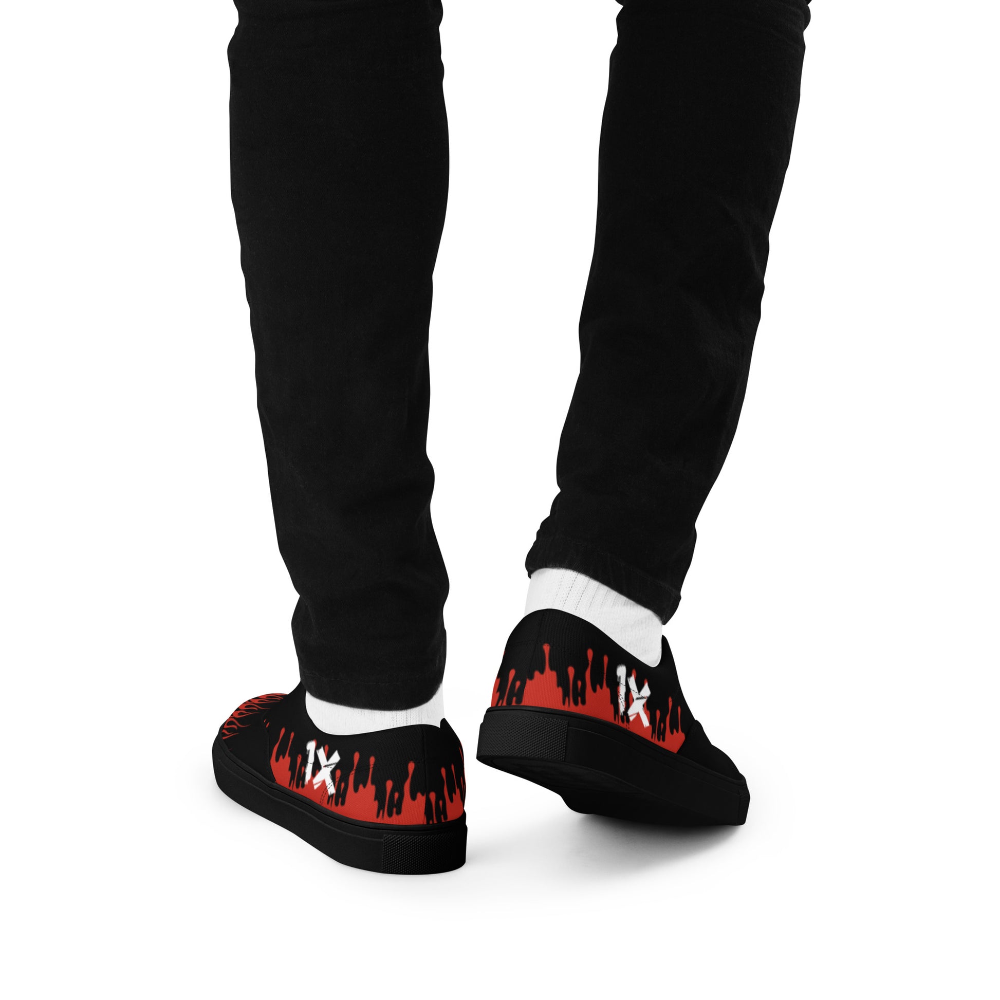 Black canvas sneakers with red flame print, worn with black pants, side view.