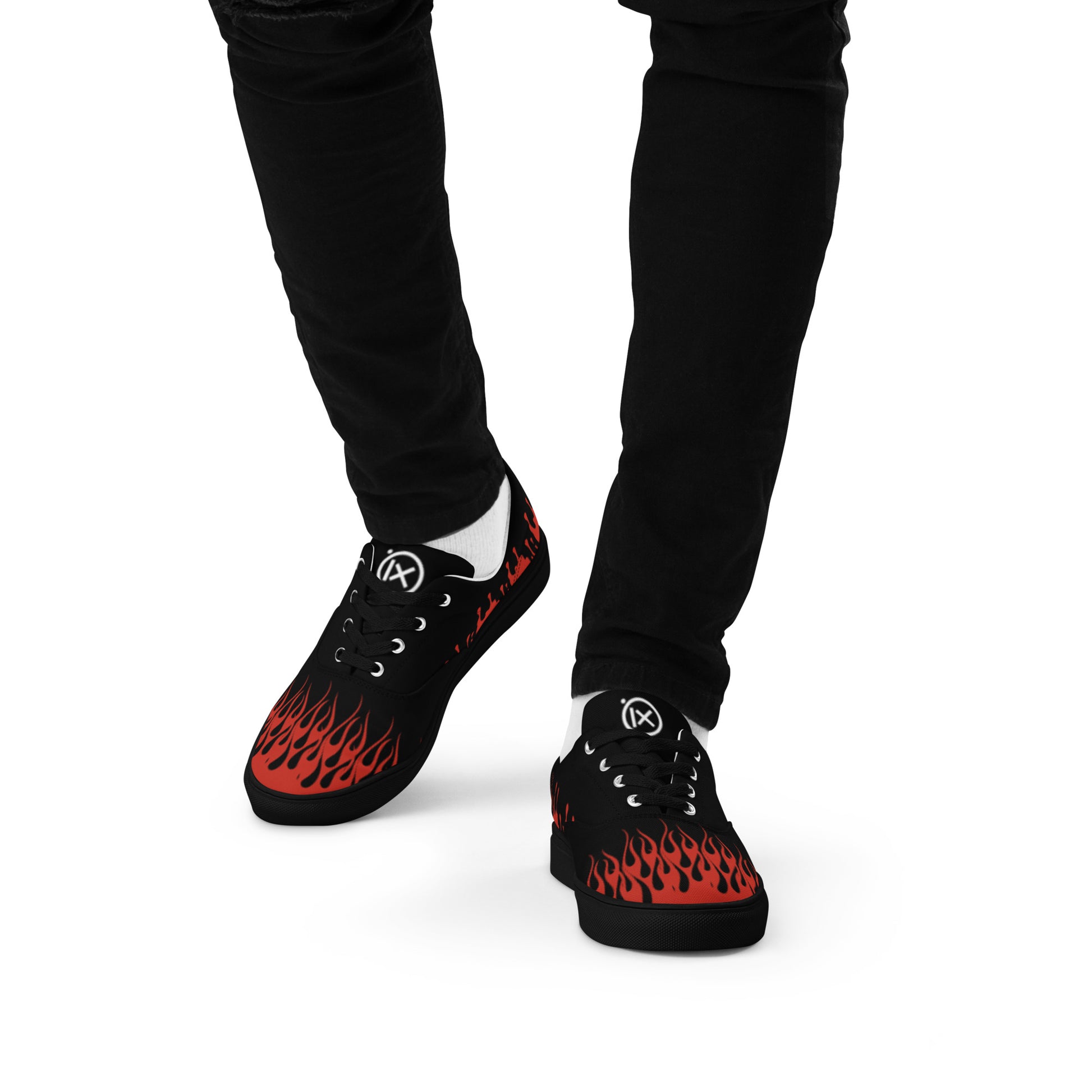 Black canvas sneakers with red flame graphic, worn with black pants, lace-up.