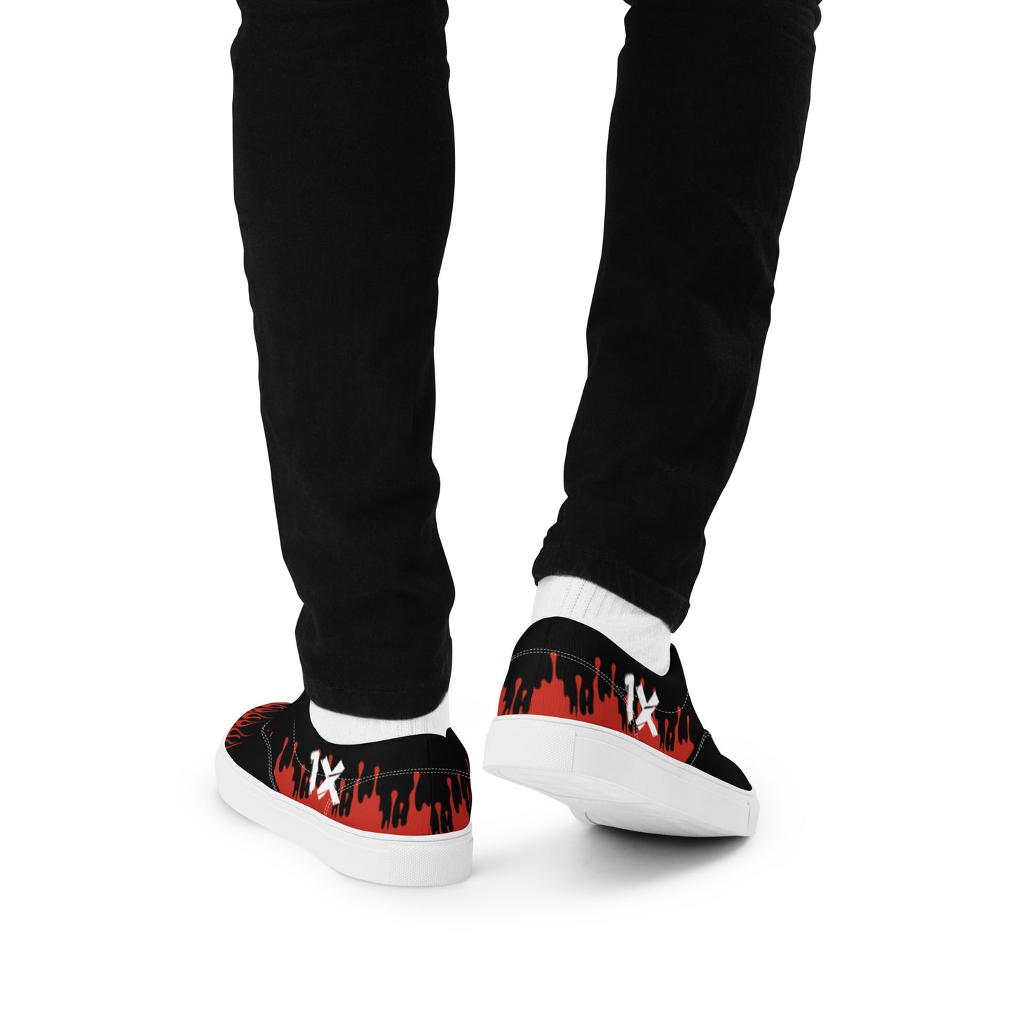 Black canvas sneakers with red flame print, worn with black pants, heel view.