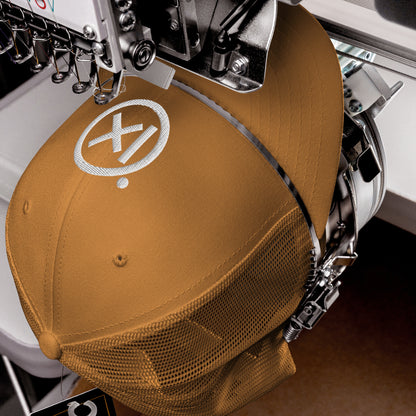 Tan trucker snapback hat with white logo patch and perforated mesh back