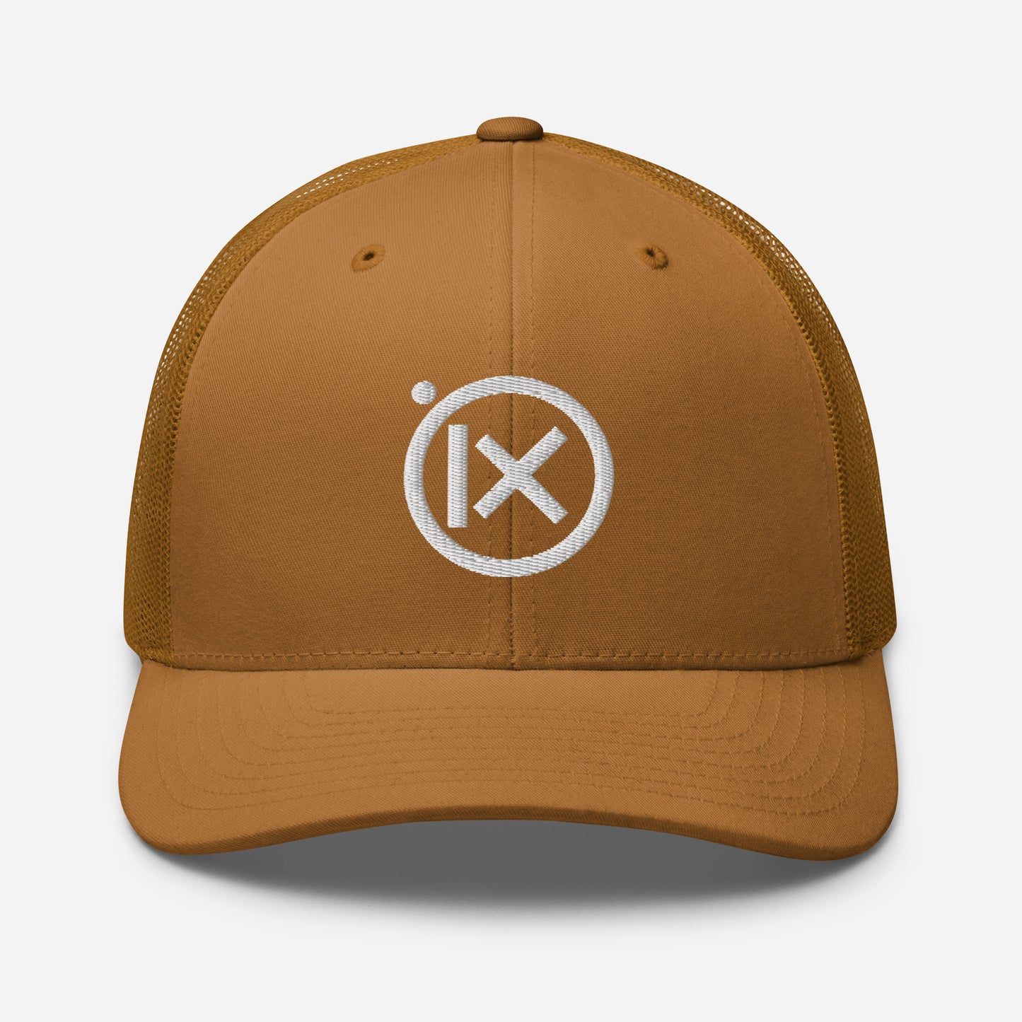 Tan trucker snapback cap with circular X logo patch and tan mesh side panels.
