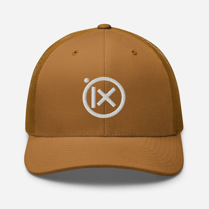 Tan trucker snapback cap with circular X logo patch and tan mesh side panels.
