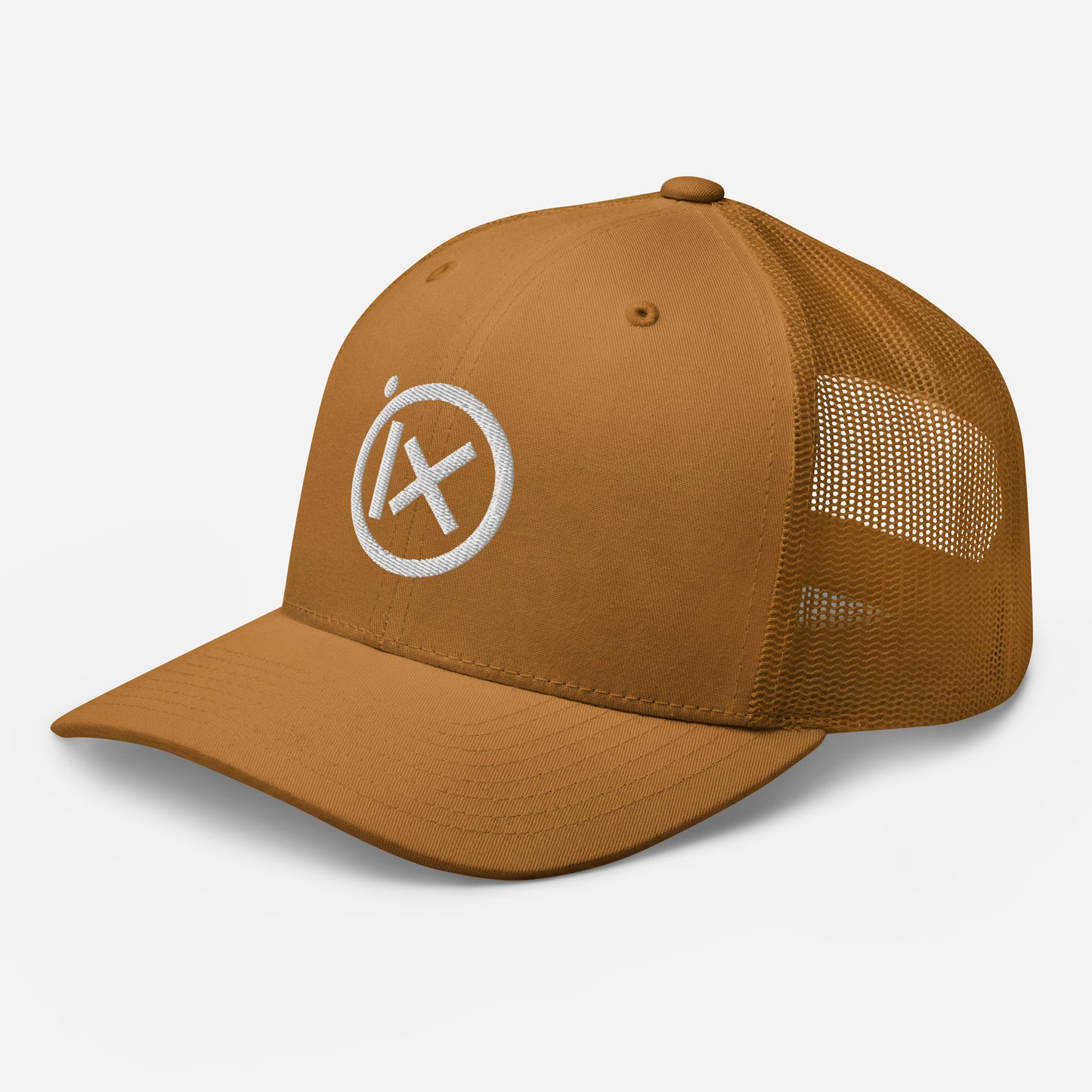Tan trucker snapback cap angled view with circular X logo patch and tan mesh side panels.