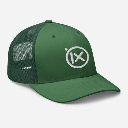 Green trucker snapback cap with circular X logo patch and curved brim over mesh panels.
