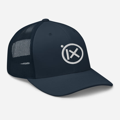 Trucker snapback cap with dark navy front, mesh back, white circular X logo patch