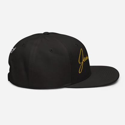 Black snapback cap with small yellow “Jevin” logo on the right side and emblem