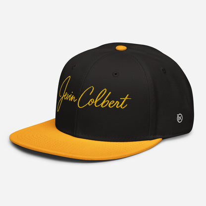 Black snapback cap with orange underside brim, Jevin Colbert logo, and side emblem