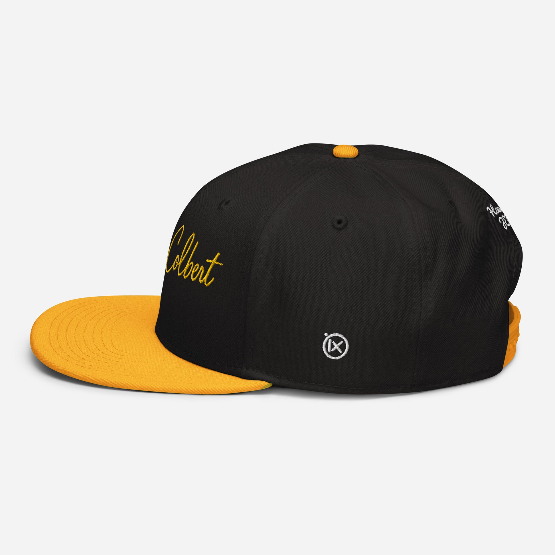 Black snapback cap with orange underside brim and small gold-toned logo on side