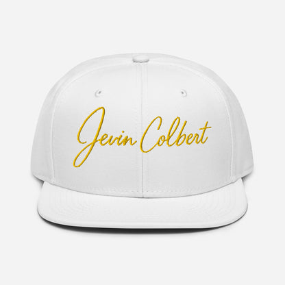 White snapback cap with yellow “Jevin Colbert” script embroidery on the front panel