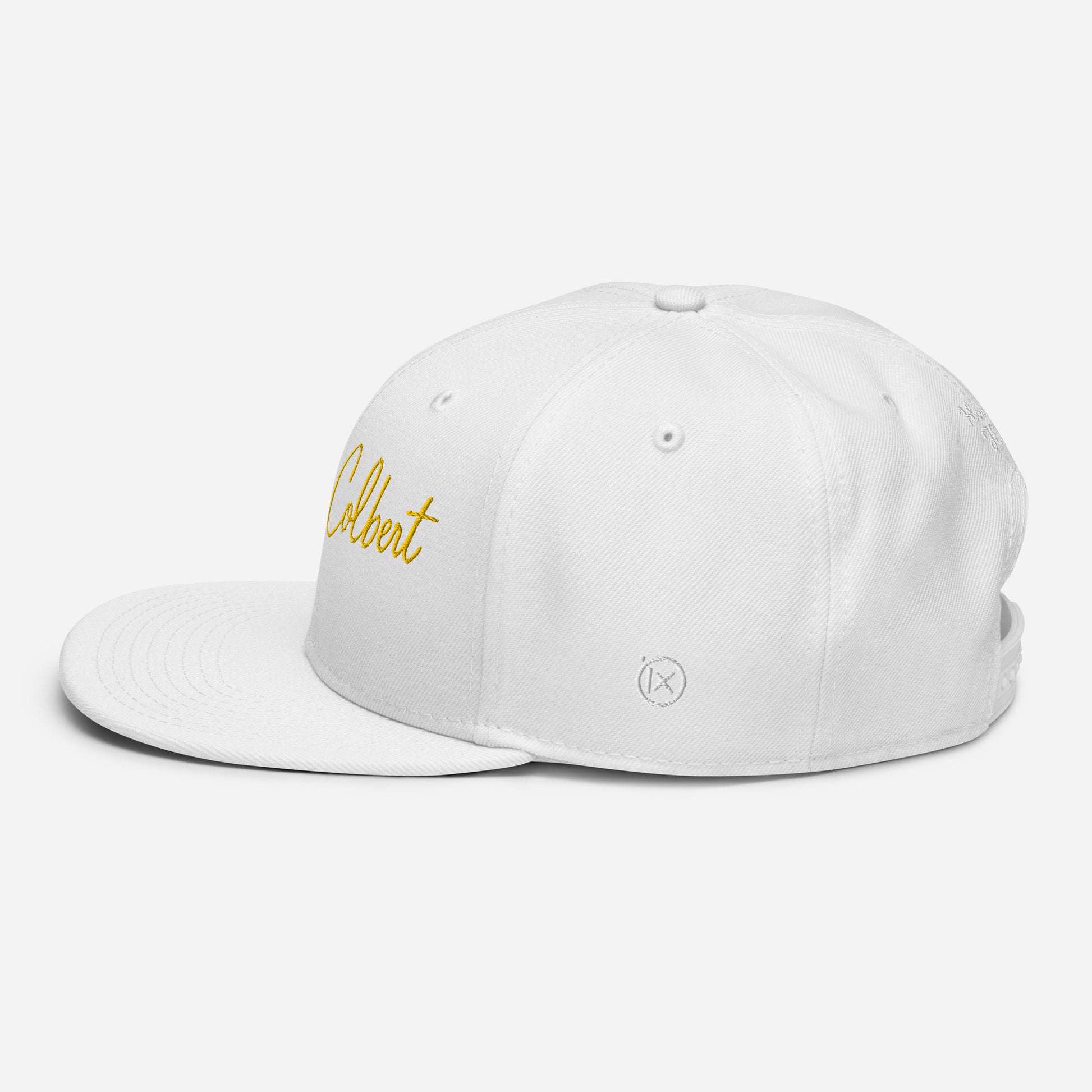 White snapback cap with yellow “Colbert” script logo on the left side and small emblem