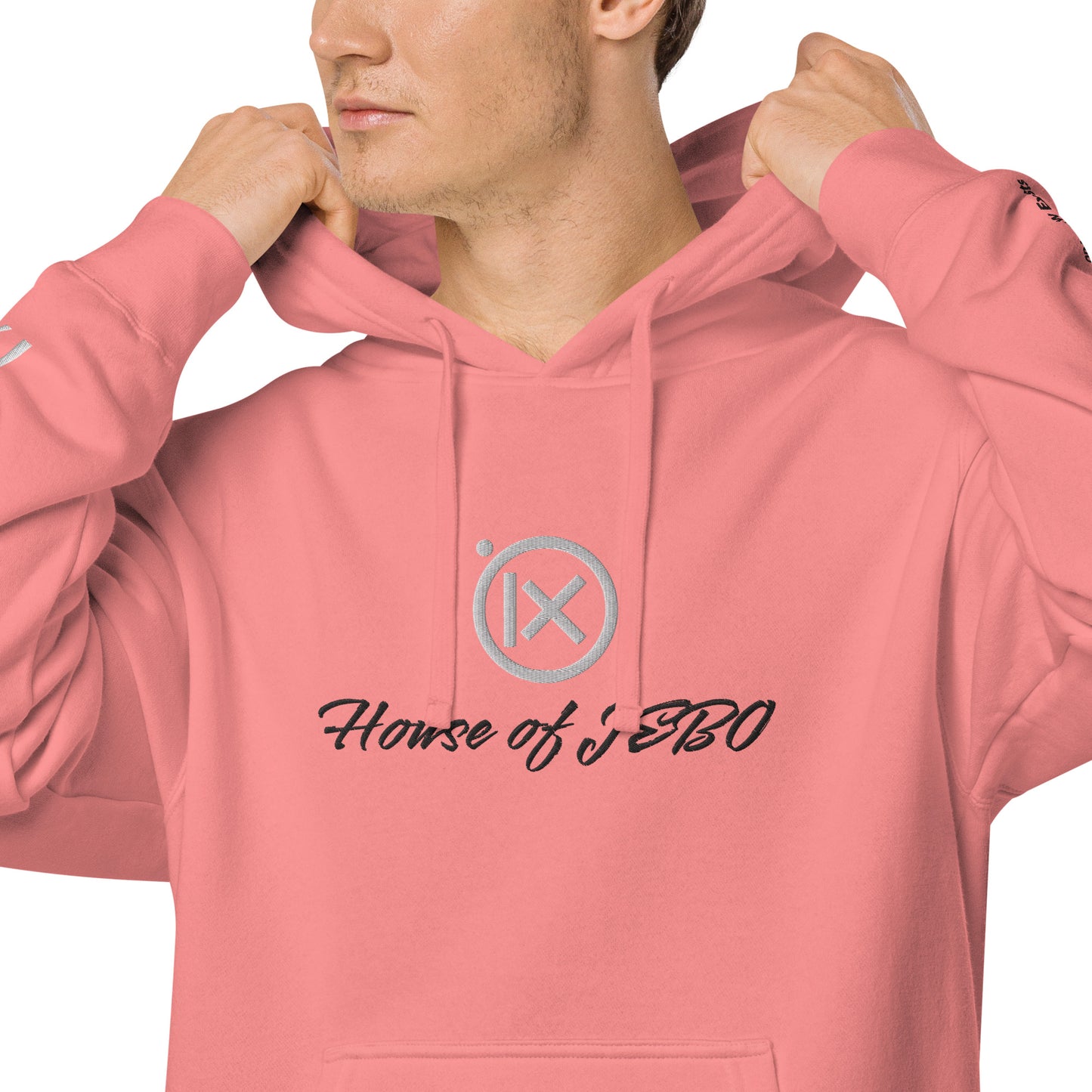 Close-up: coral-pink hoodie with hood drawstrings and House of JERO chest graphic